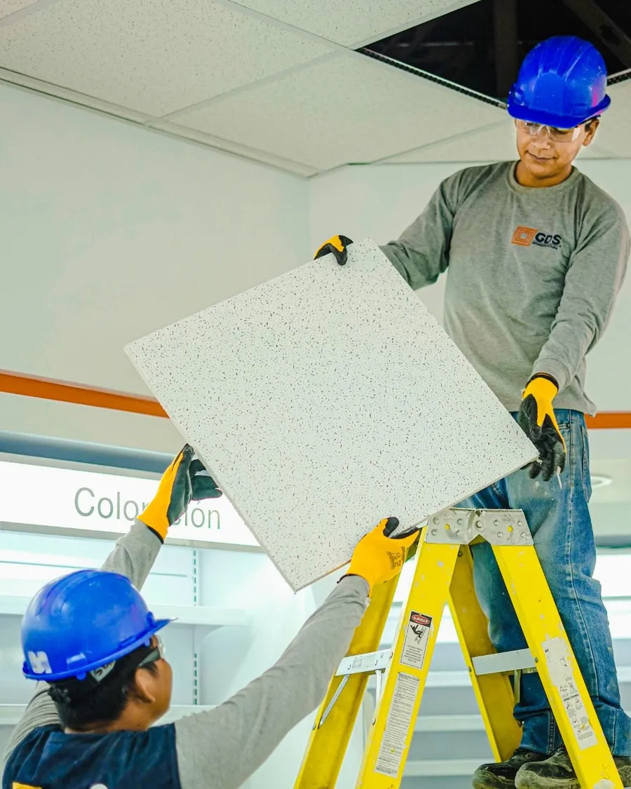 Dos técnicos de GDS Infraestructura instalando cielo raso en un local comercial en obra