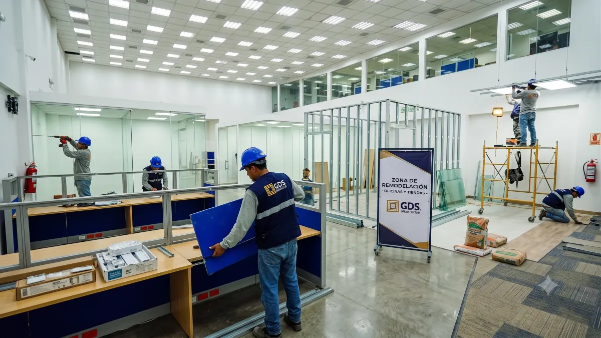 Técnicos de GDS interviniendo instalaciones eléctricas y pantallas en un local comercial de fachada naranja sin detener su operación