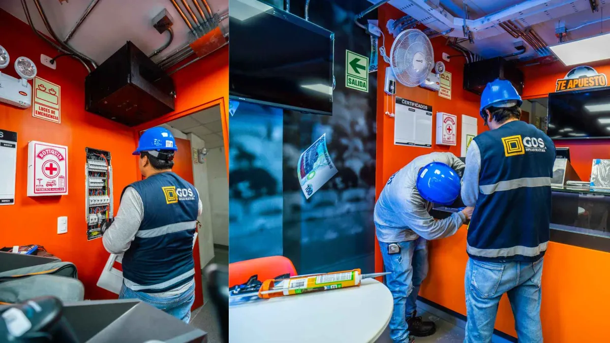 Técnico de GDS con guantes dieléctricos interviniendo un tablero eléctrico abierto en la zona de servicio de una tienda