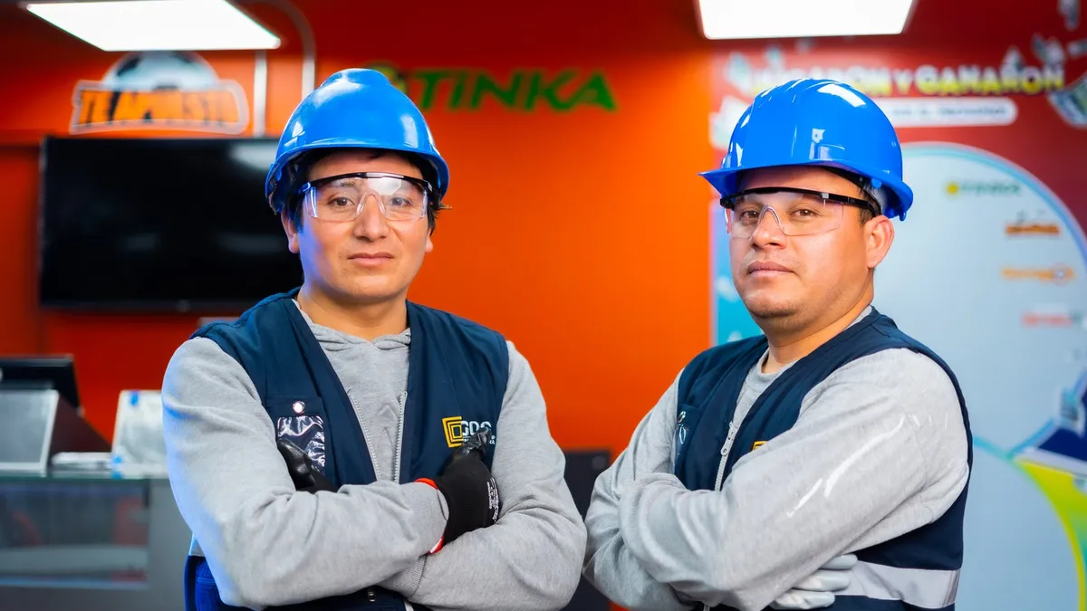 Dos técnicos de GDS Infraestructura en el interior de un local Tinka implementado, con señalética y mobiliario instalados